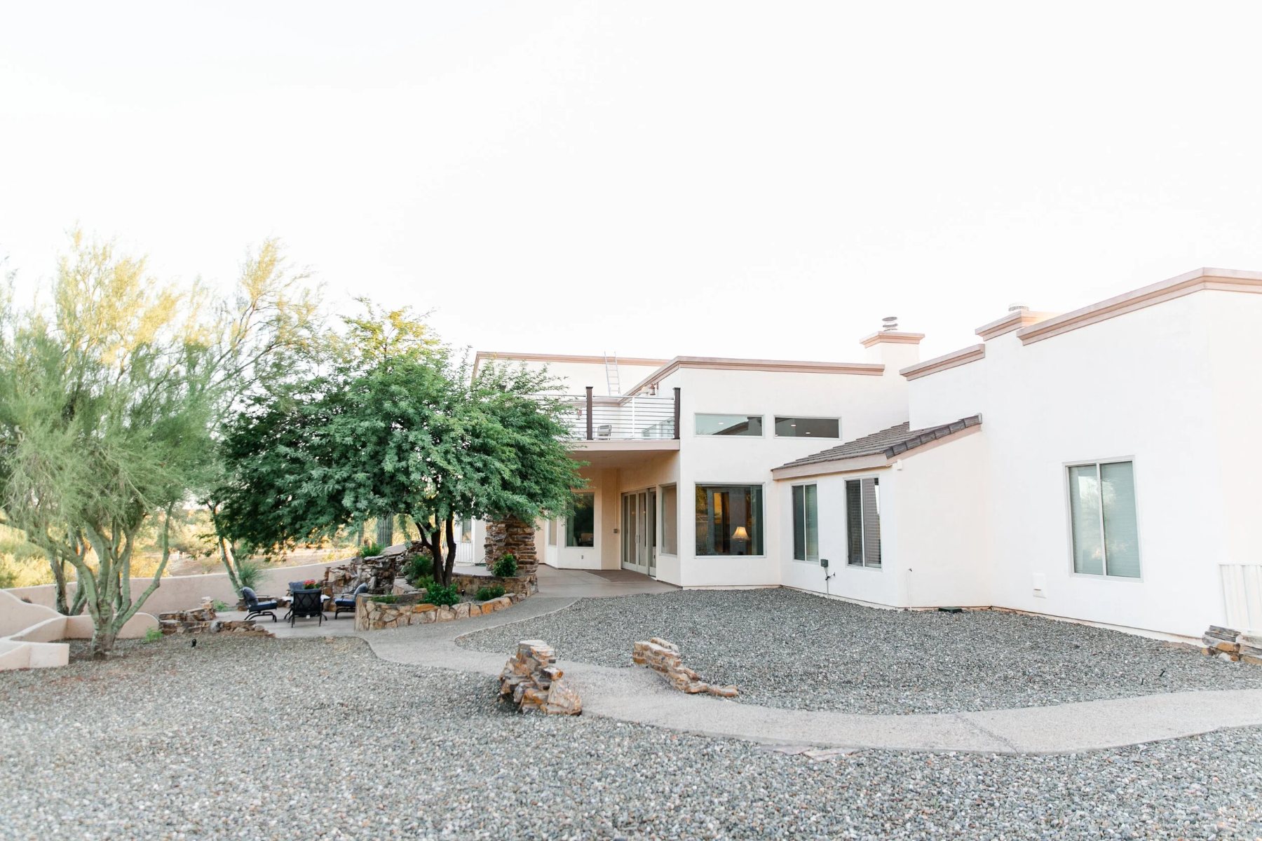 Back of the house with a covered patio, palo verde trees and an upper deck