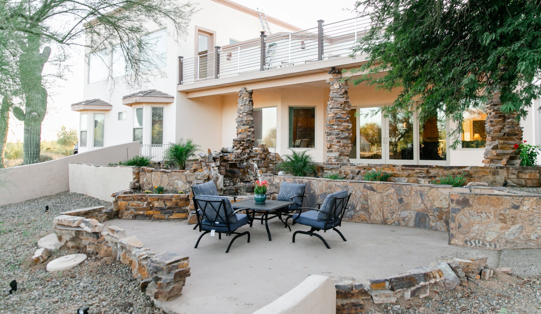 Stone-walled back patio with cushioned seating around a small fountain