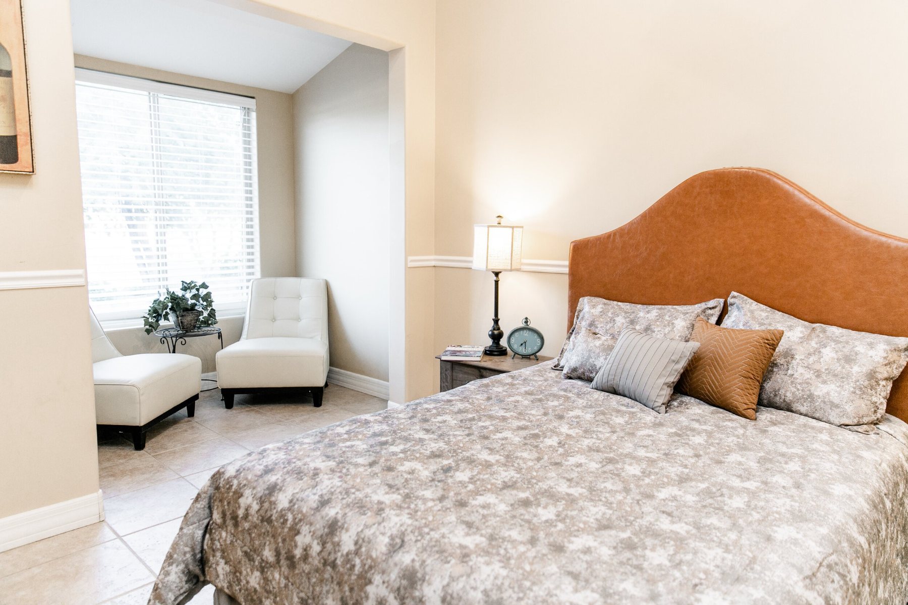 Resident bedroom with an upholstered headboard and a sunny sitting nook