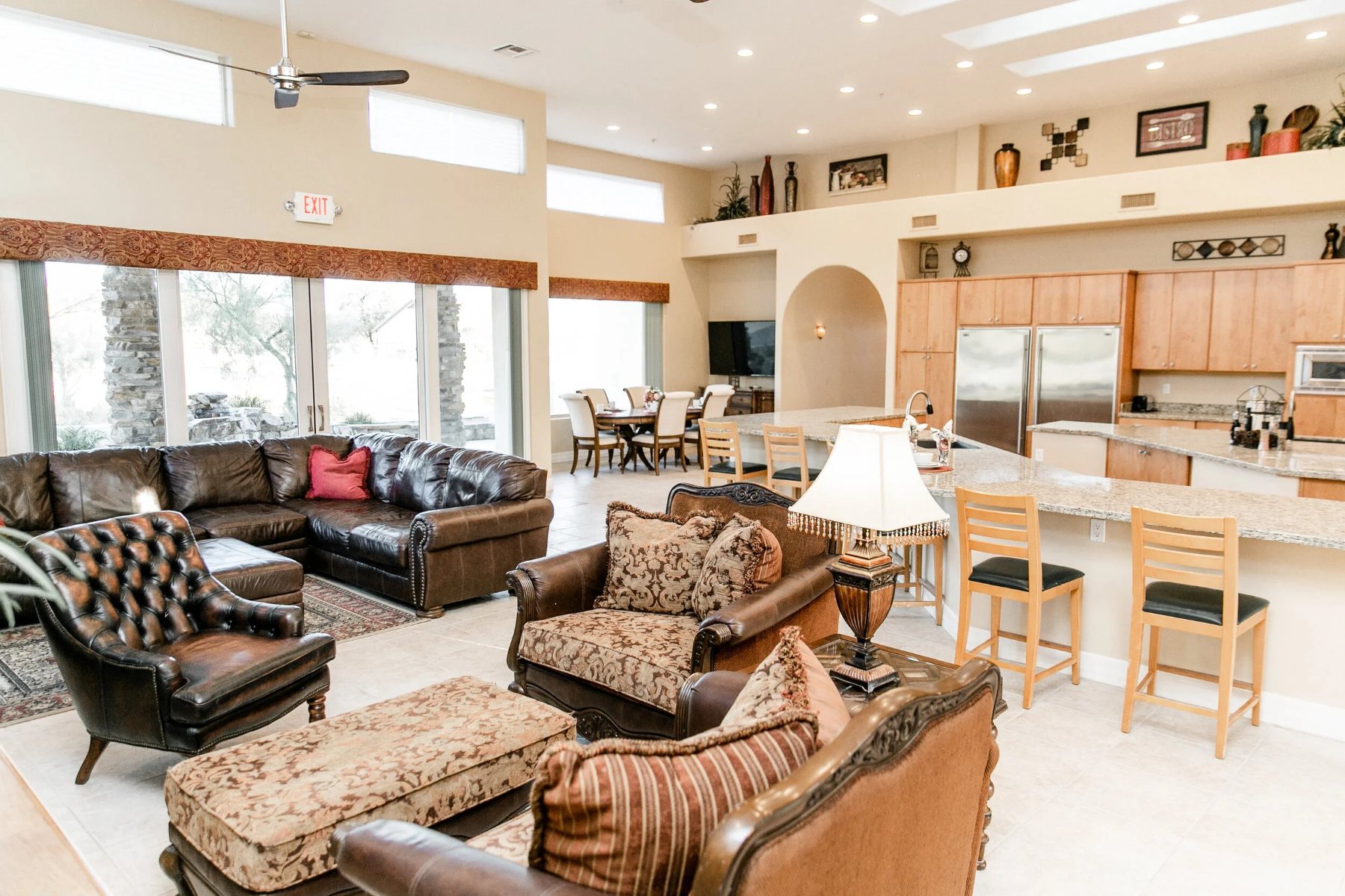Great room with leather seating, tall windows and the open kitchen beyond